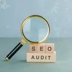Seo analysis and business concept with wooden blocks with words on it, magnifying glass on sage color background side view. horizontal image